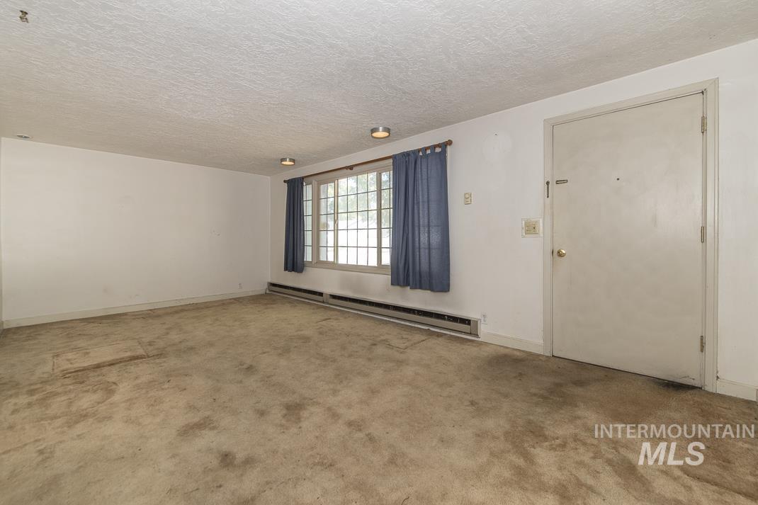 Unfurnished room with baseboard heating, a textured ceiling, and light carpet