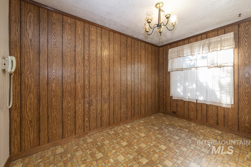 Empty room featuring wooden walls, brick patterned floors, and a chandelier