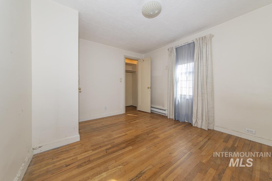Unfurnished bedroom featuring light wood-style floors and baseboard heating