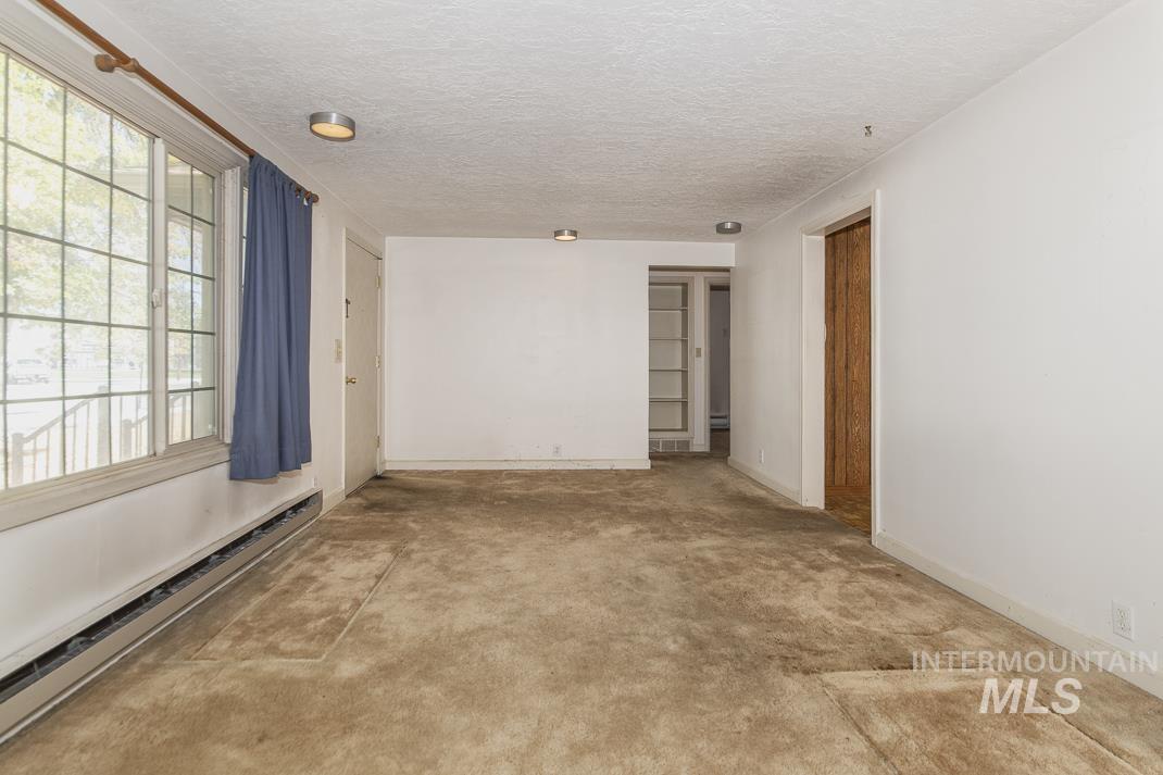 Unfurnished room with baseboard heating and a textured ceiling