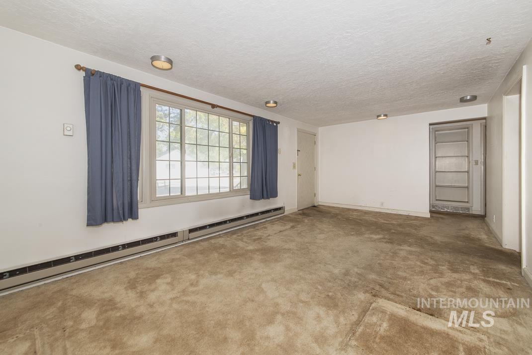 Unfurnished room featuring baseboard heating and a textured ceiling