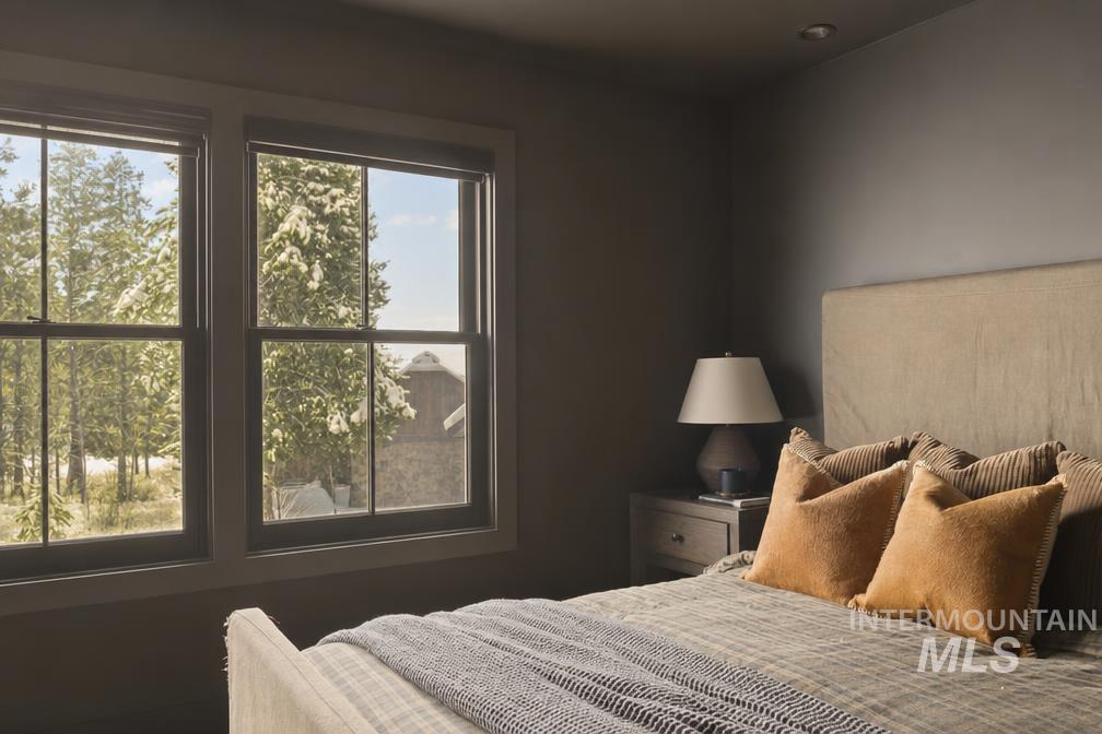 Dual windows with tree-lined scenery, featuring a recessed ceiling light, wall-to-wall carpeting, and a built-in bedside table with a table lamp