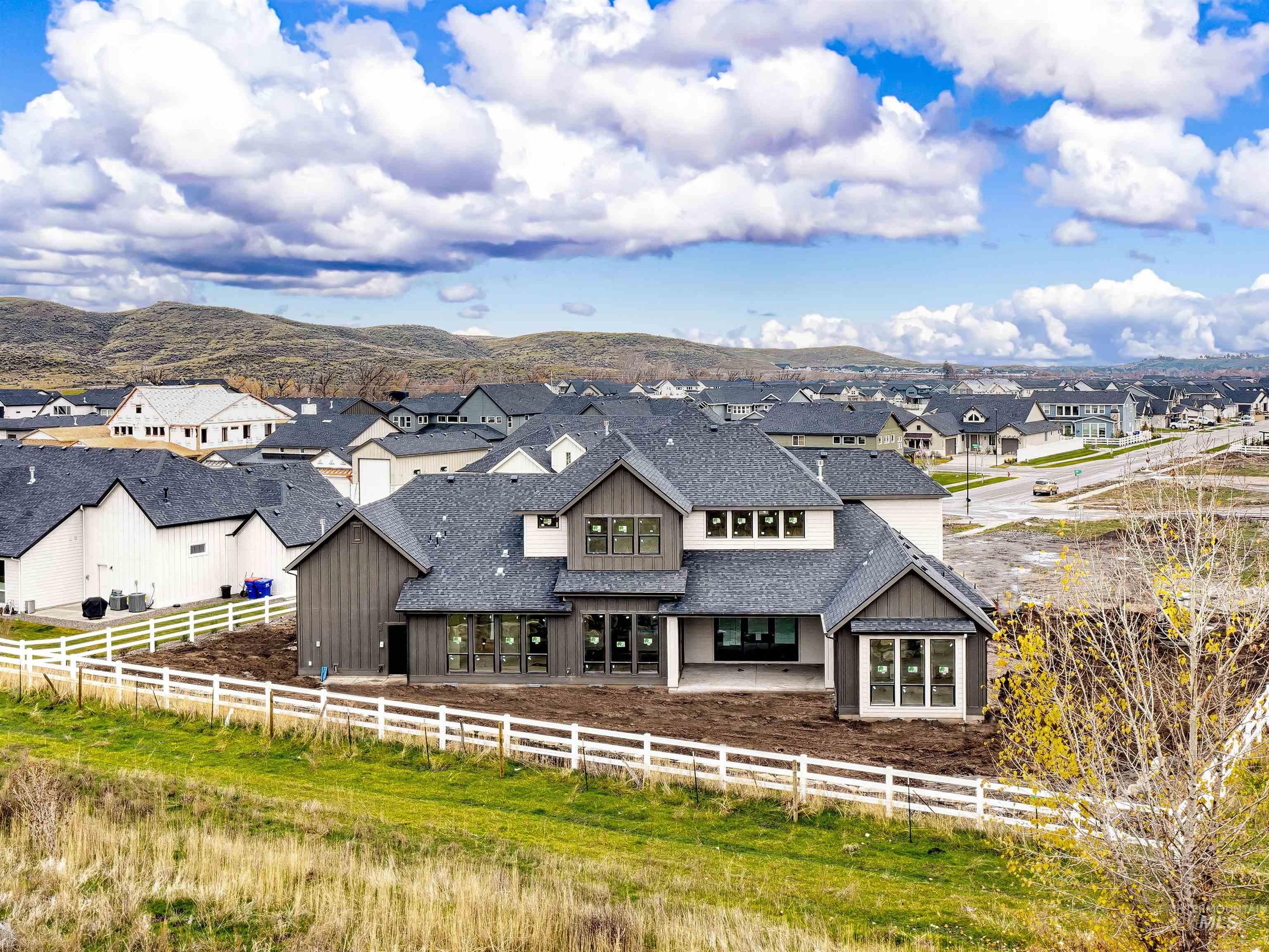 Back of property featuring a fenced front yard, a shingled roof, a residential view, and board and batten siding
