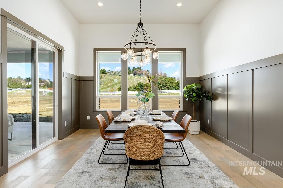 Dining room featuring a decorative wall, wainscoting, light wood-style flooring, and a chandelier