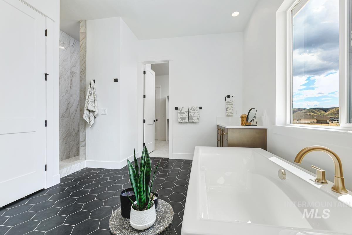 Bathroom with a freestanding tub, a marble finish shower, recessed lighting, vanity, and dark tile patterned floors