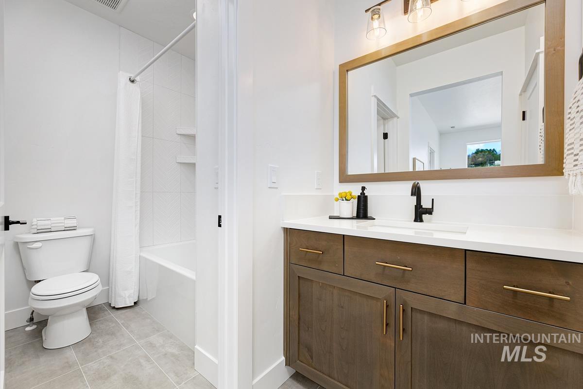 Full bath with vanity, shower / bath combination with curtain, and light tile patterned flooring