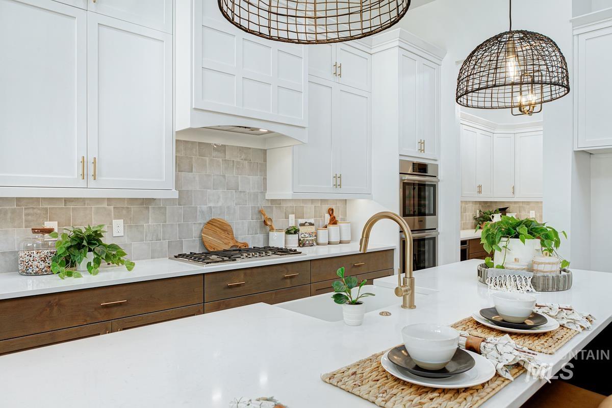 Kitchen with white cabinetry, decorative backsplash, stainless steel appliances, and light stone countertops