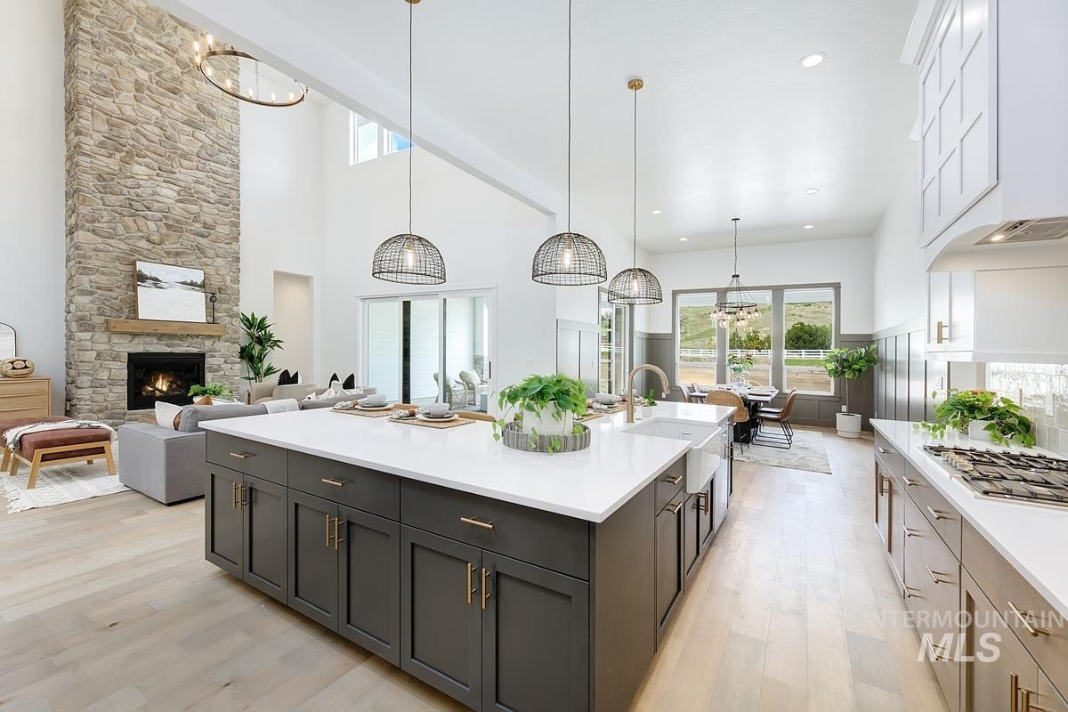 Kitchen with open floor plan, a high ceiling, a chandelier, light wood-style floors, and a fireplace