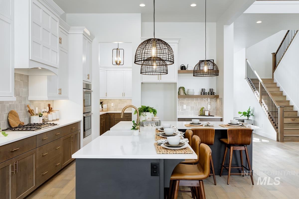 Kitchen with a kitchen island with sink, a breakfast bar, pendant lighting, open shelves, and white cabinetry