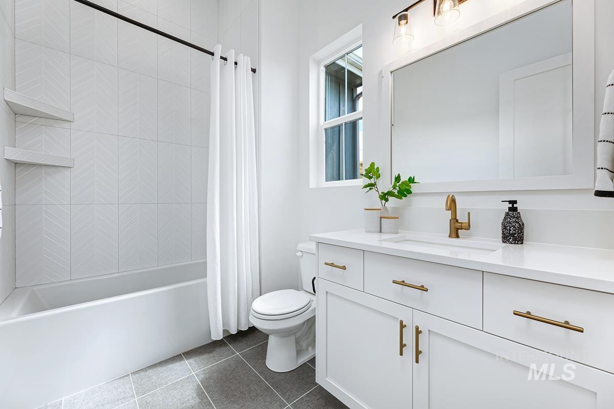 Bathroom with vanity, shower / bath combo, and dark tile patterned floors
