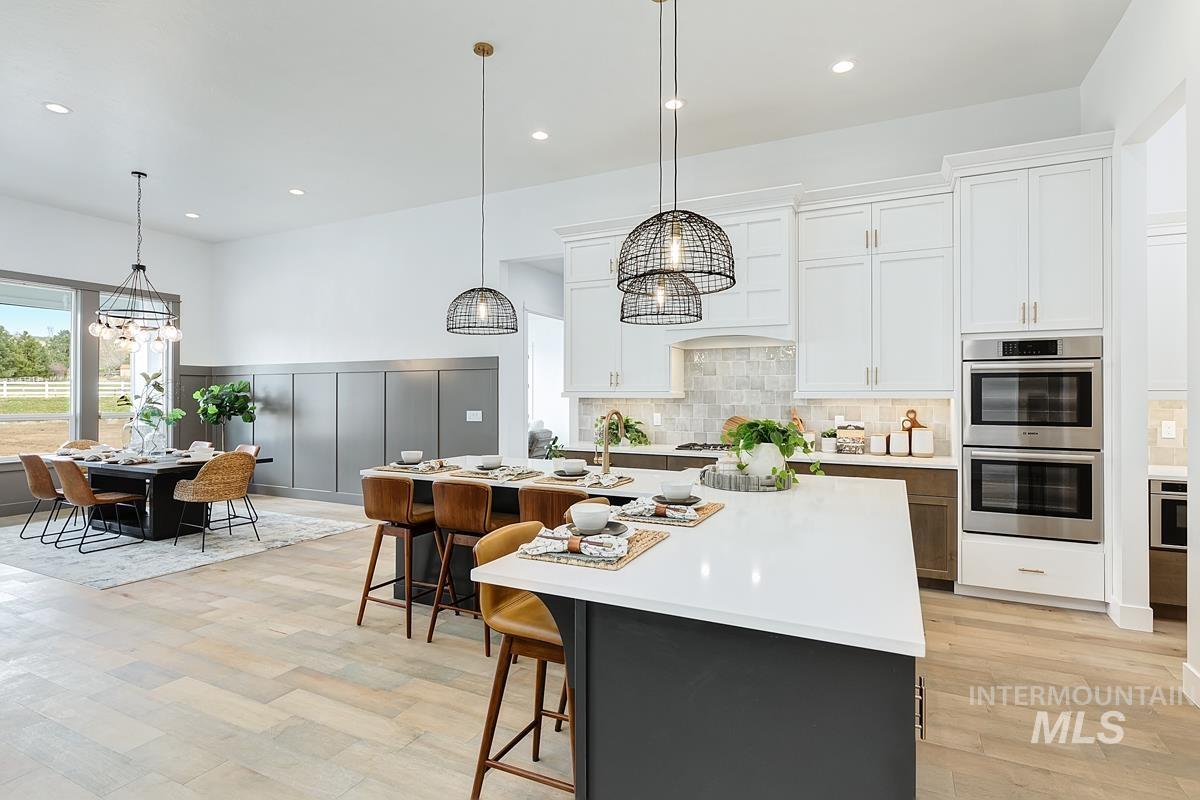 Kitchen with a breakfast bar, white cabinetry, a center island with sink, stainless steel appliances, and a chandelier