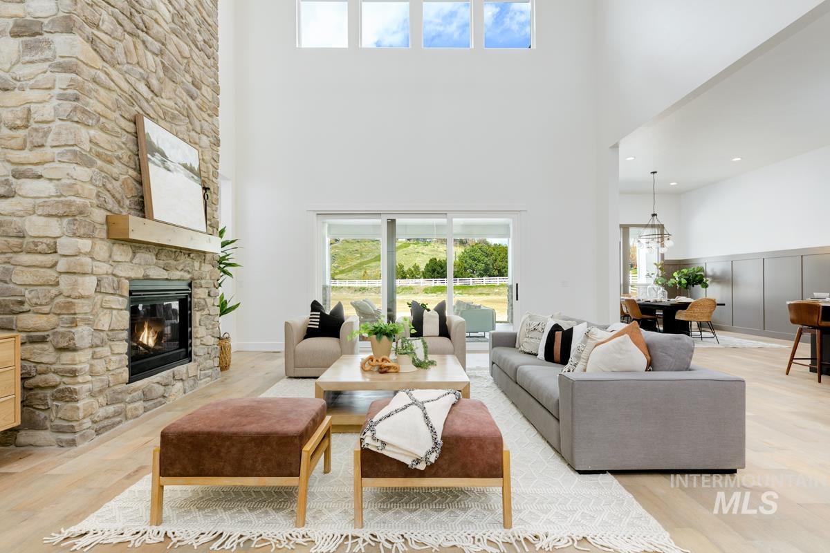 Living room featuring light wood finished floors, a fireplace, and a towering ceiling