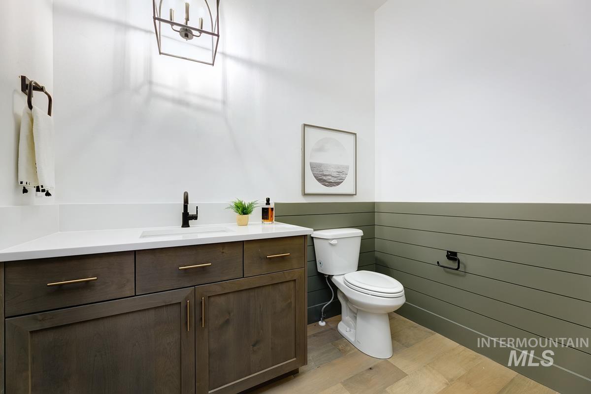 Half bath with a wainscoted wall, vanity, and light wood-style flooring