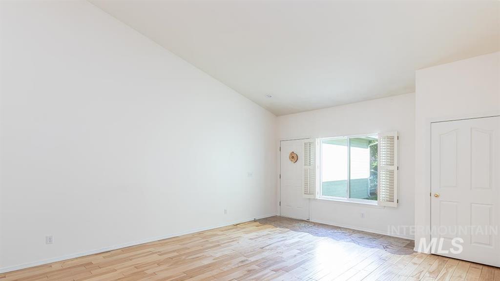 Unfurnished room with light wood-style flooring and vaulted ceiling