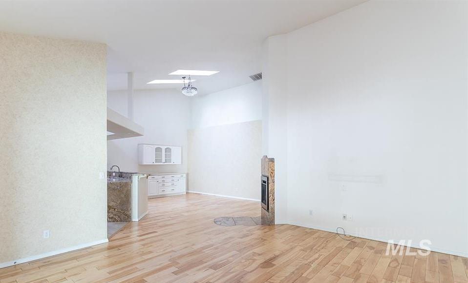 Unfurnished living room featuring light wood-style floors, a high ceiling, and a fireplace with flush hearth