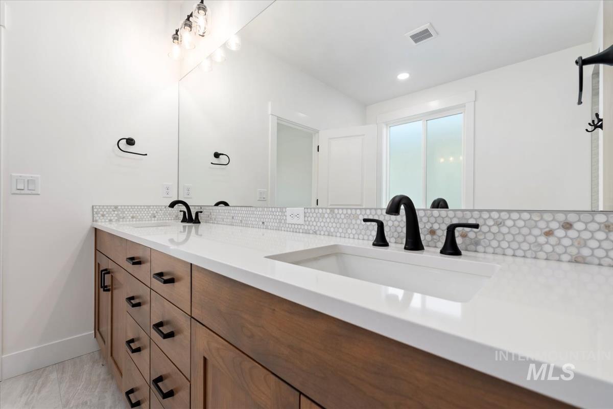 Double vanity with wood-finish cabinetry, white countertops, and integrated rectangular sinks