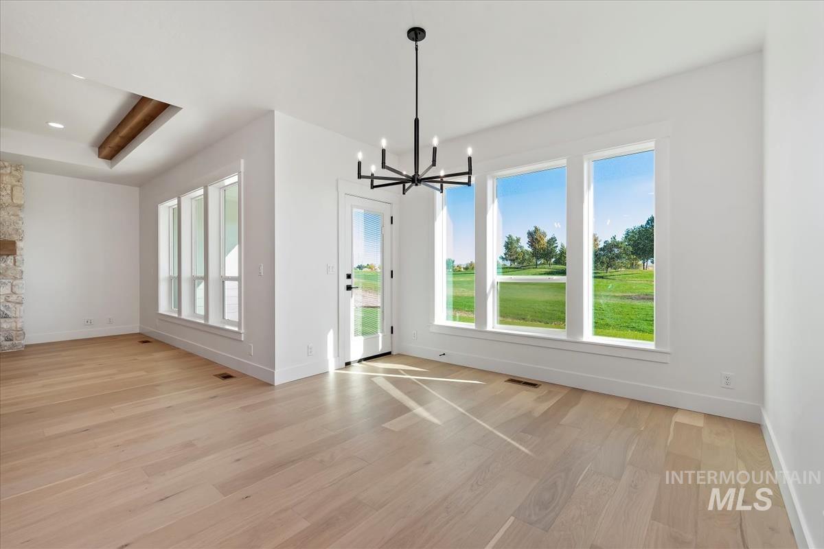 Open-concept living space featuring light wood-finish flooring, white walls, and a contemporary black chandelier