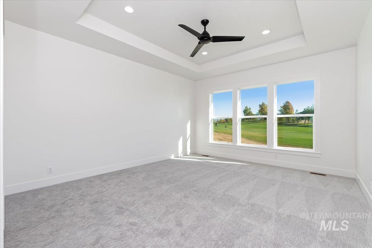 Room featuring triple windows overlooking a green landscape, light gray carpet, and white walls