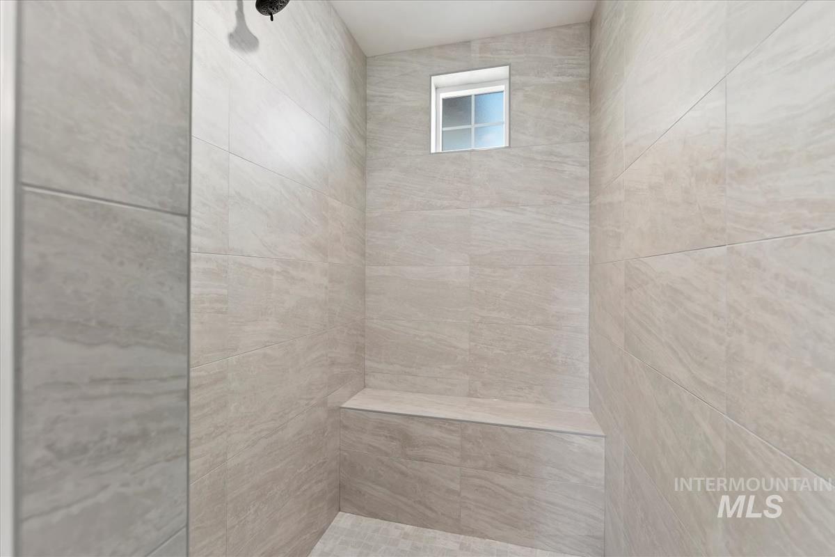Walk-in shower featuring large format tile, an integrated bench, and a privacy window