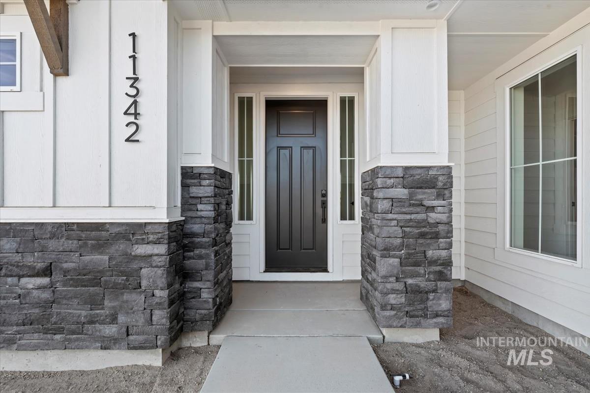 Inviting entryway with a paneled dark-finish door, complemented by sidelight windows and a concrete pathway