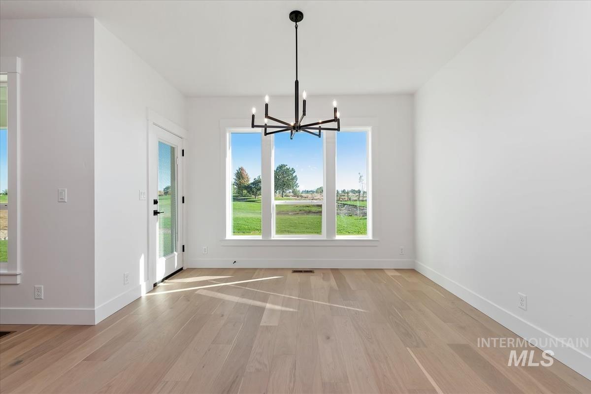 Spacious room featuring wood-finish flooring, white baseboards, and a modern black chandelier