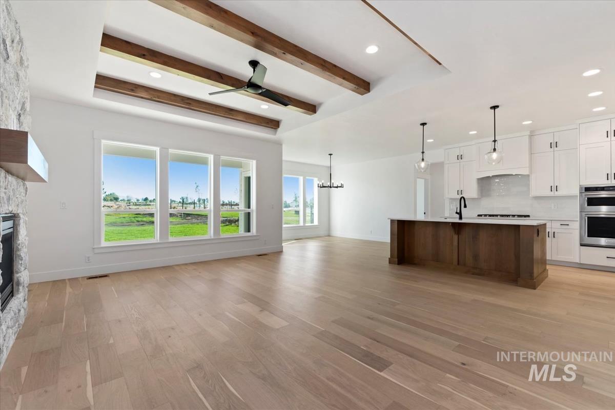 Expansive living space featuring wood-finish flooring and a stone-clad fireplace