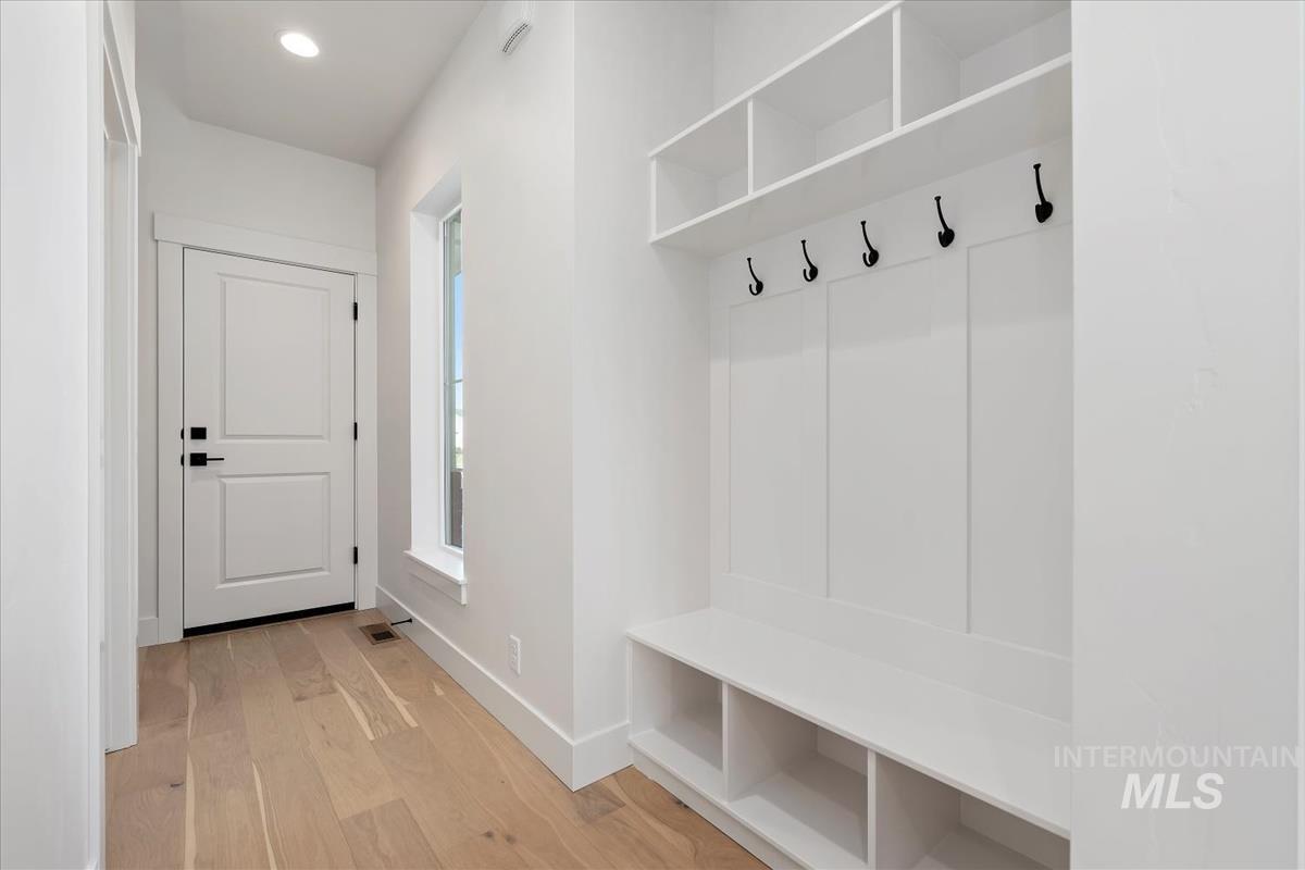 Entryway featuring a built-in bench with integrated shelving, storage cubbies, and overhead shelving