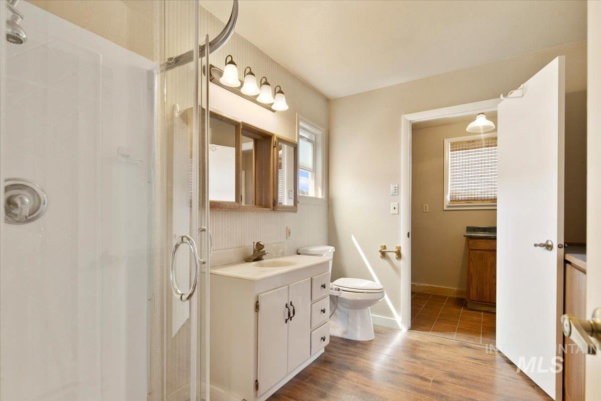 Bathroom featuring a stall shower, vanity, and wood finished floors