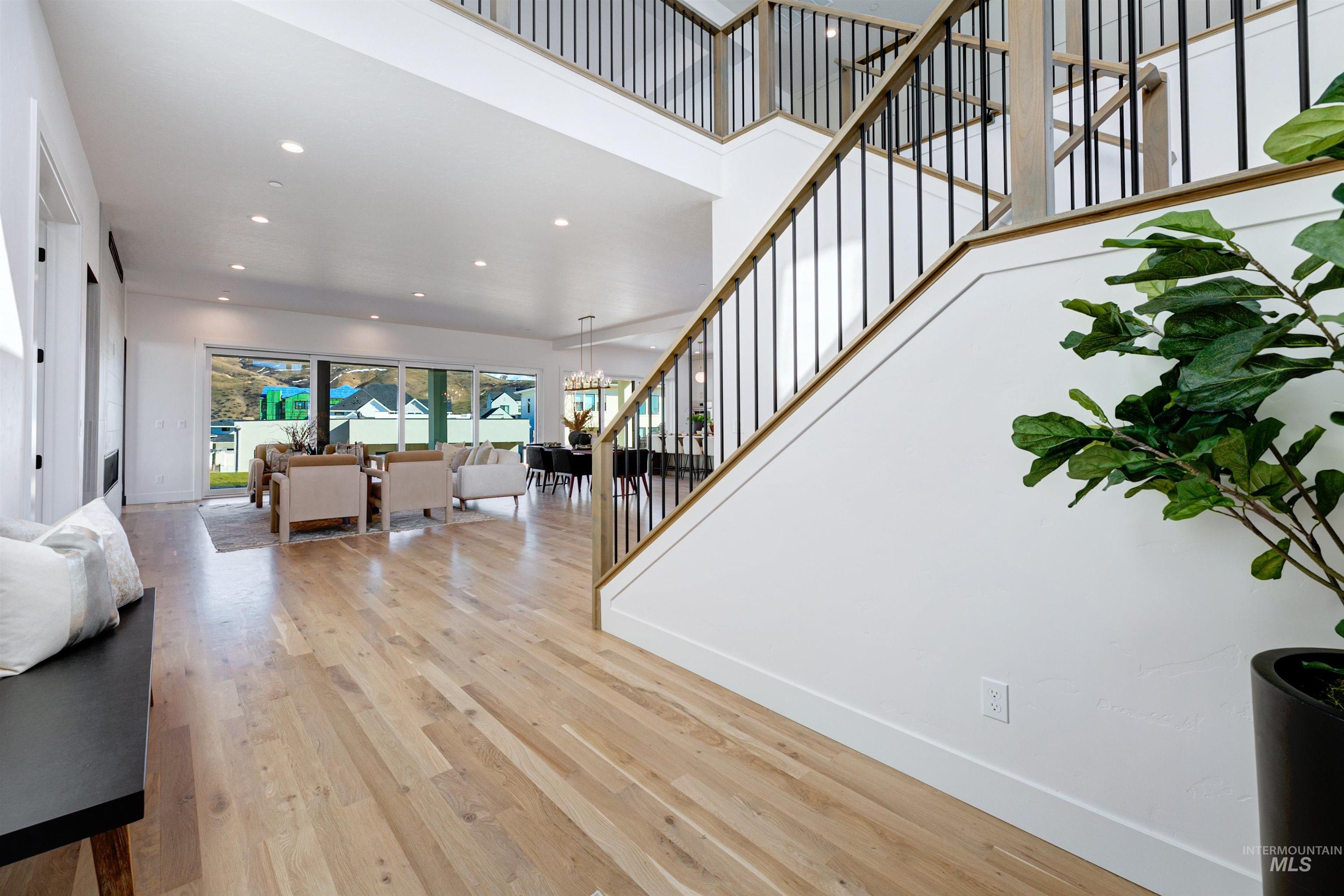 Living room featuring recessed lighting, light wood-style flooring, a chandelier, a towering ceiling, and stairway