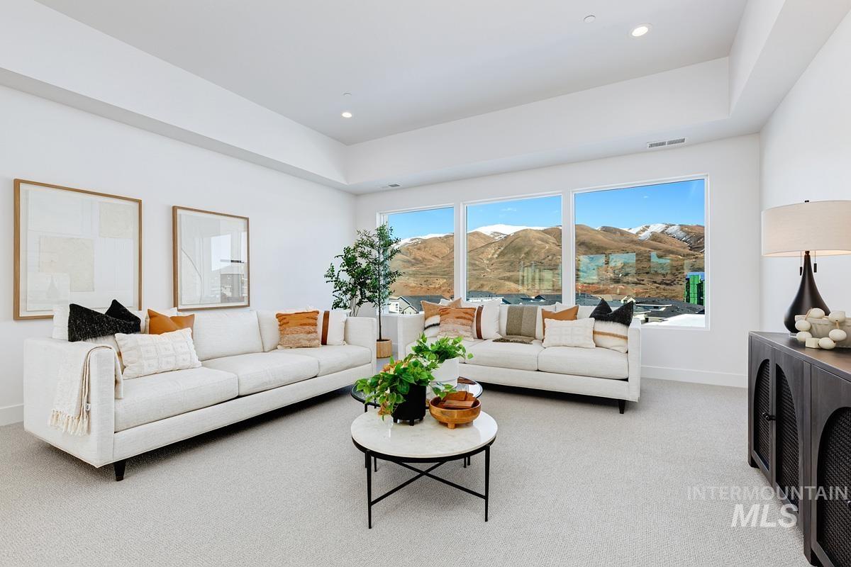 Carpeted living area with a raised ceiling, recessed lighting, and a mountain view