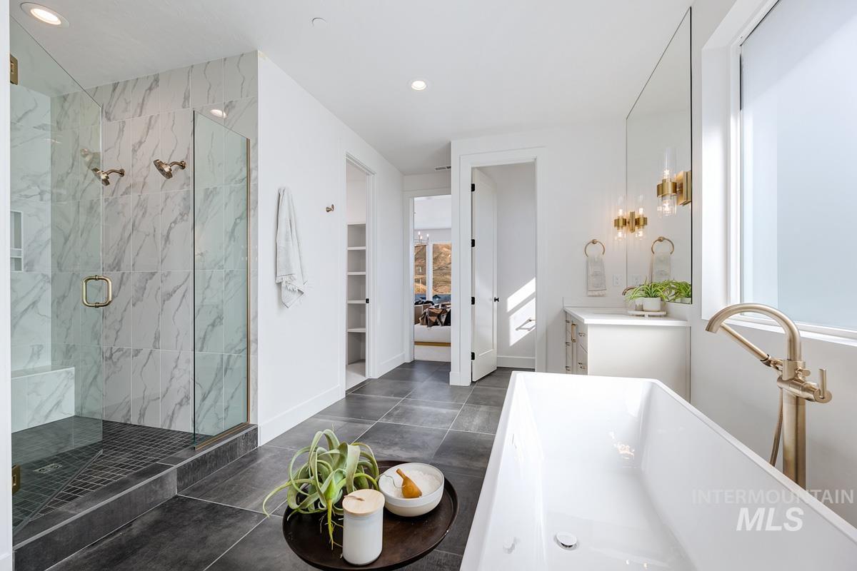 Bathroom with vanity, a spacious closet, recessed lighting, a freestanding tub, and a marble finish shower