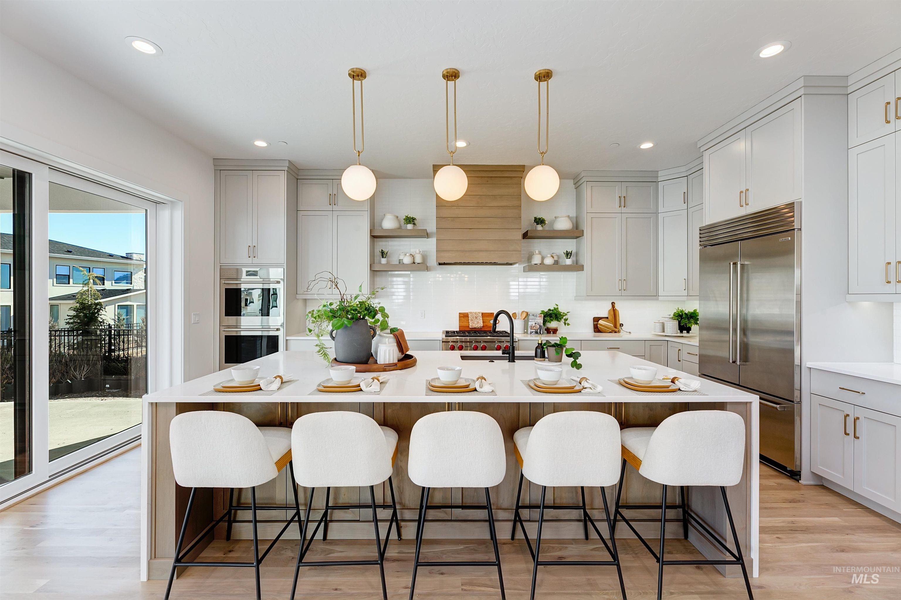 Kitchen featuring hanging light fixtures, a breakfast bar, light stone counters, appliances with stainless steel finishes, and an island with sink