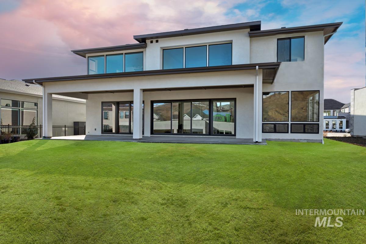 Back of property at dusk featuring a patio area, a yard, and stucco siding