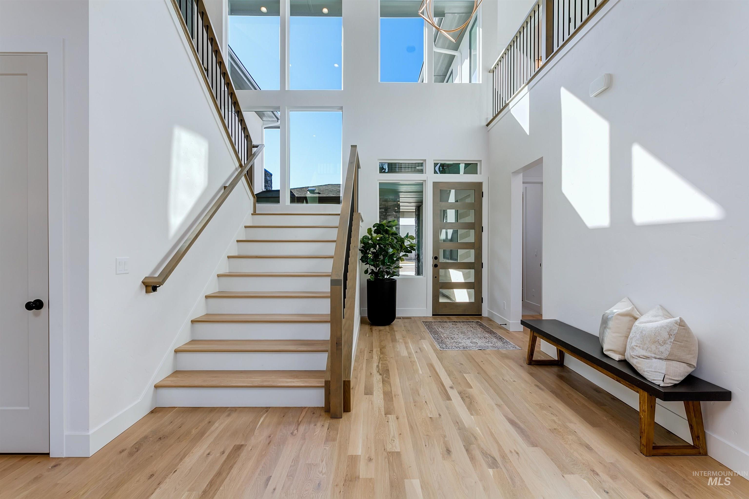 Entryway featuring light wood-style flooring, stairway, and a high ceiling