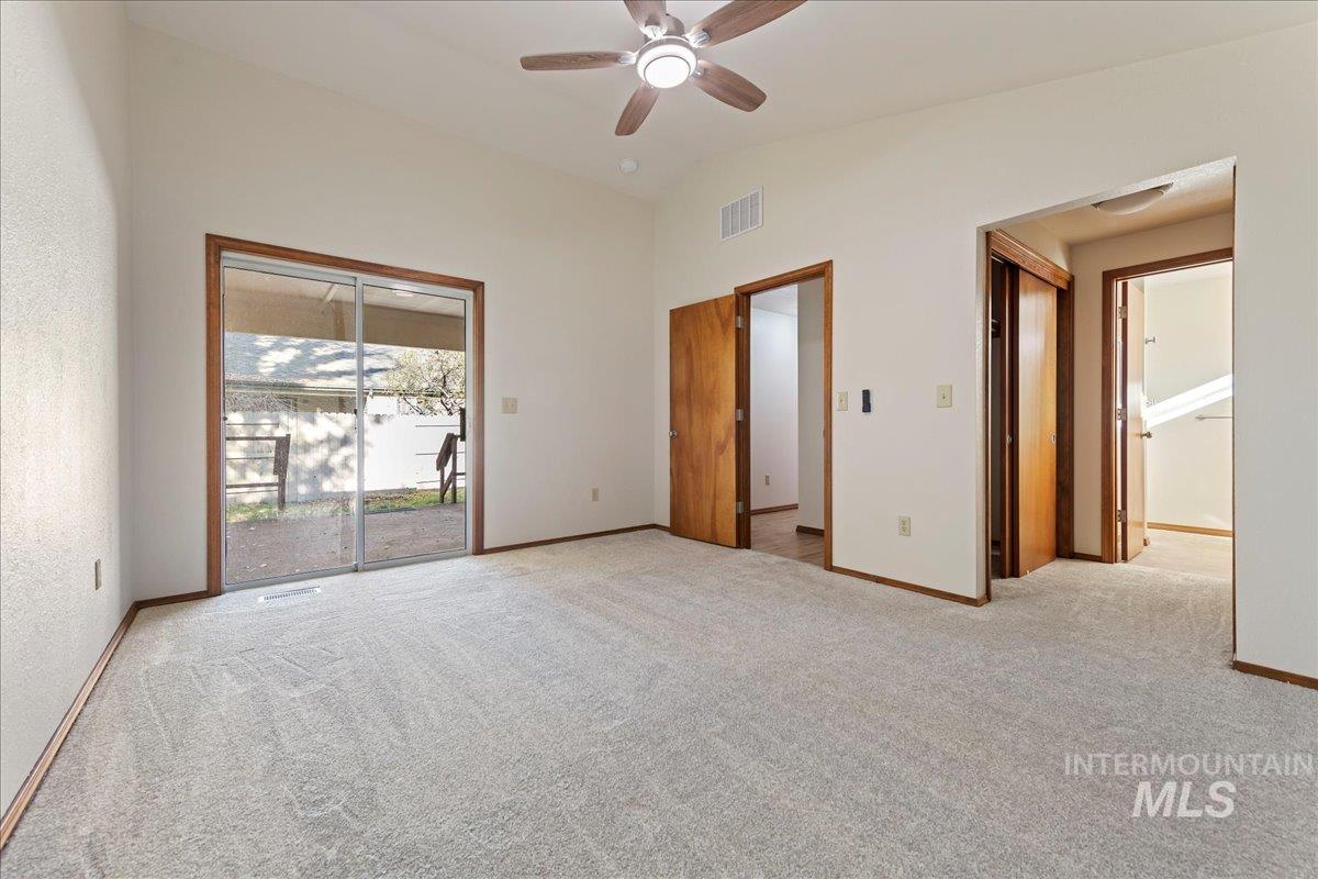 Unfurnished bedroom with access to outside, light carpet, a ceiling fan, and vaulted ceiling
