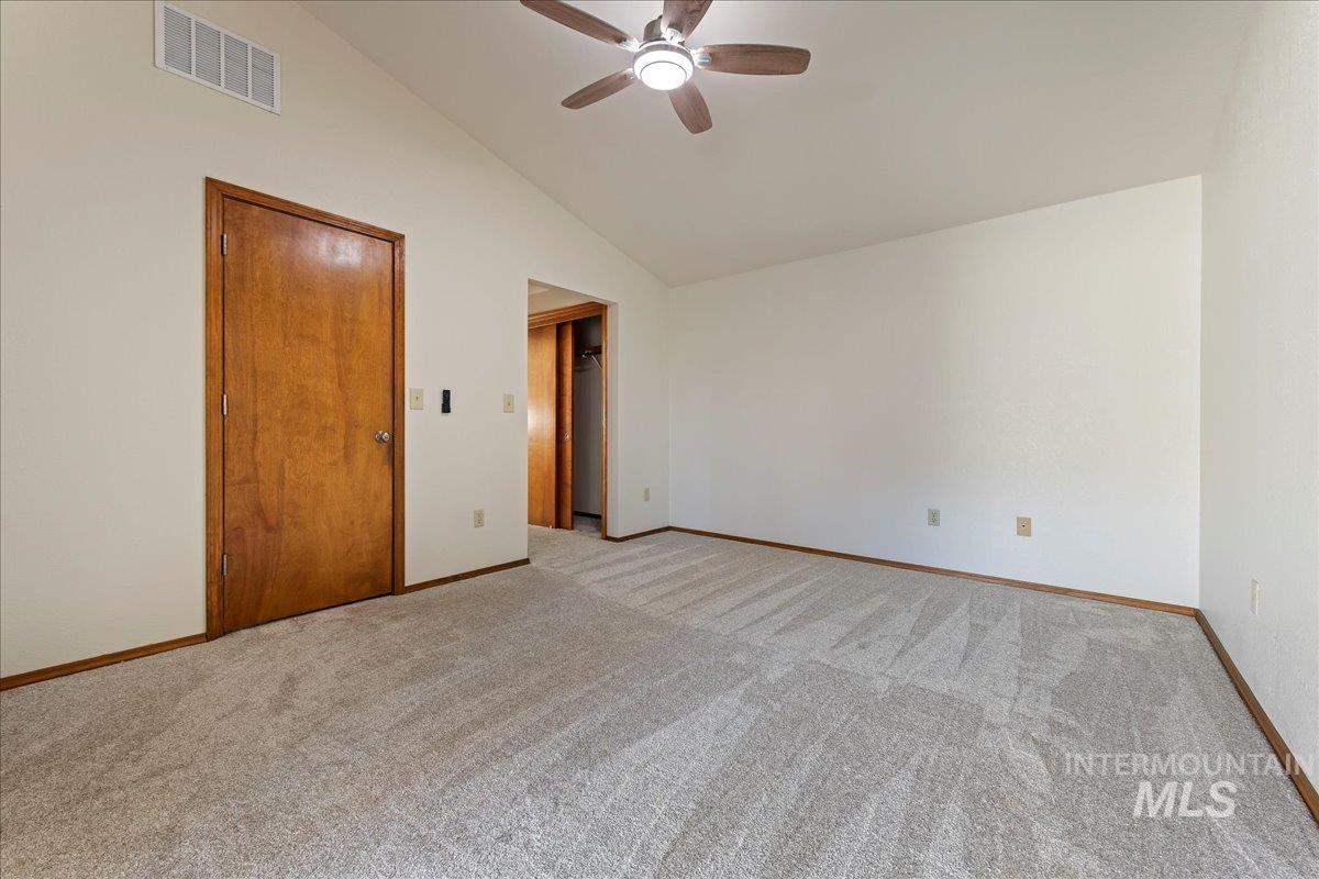 Spare room featuring light colored carpet, a ceiling fan, and high vaulted ceiling