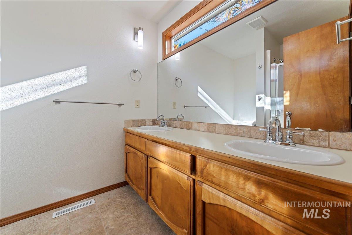 Bathroom featuring a stall shower and double vanity