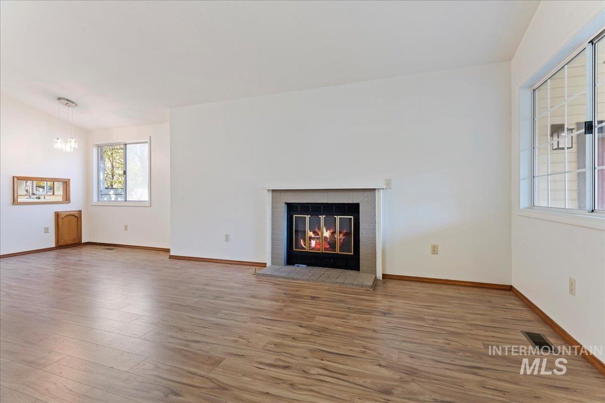 Unfurnished living room with wood finished floors, a fireplace, and a chandelier