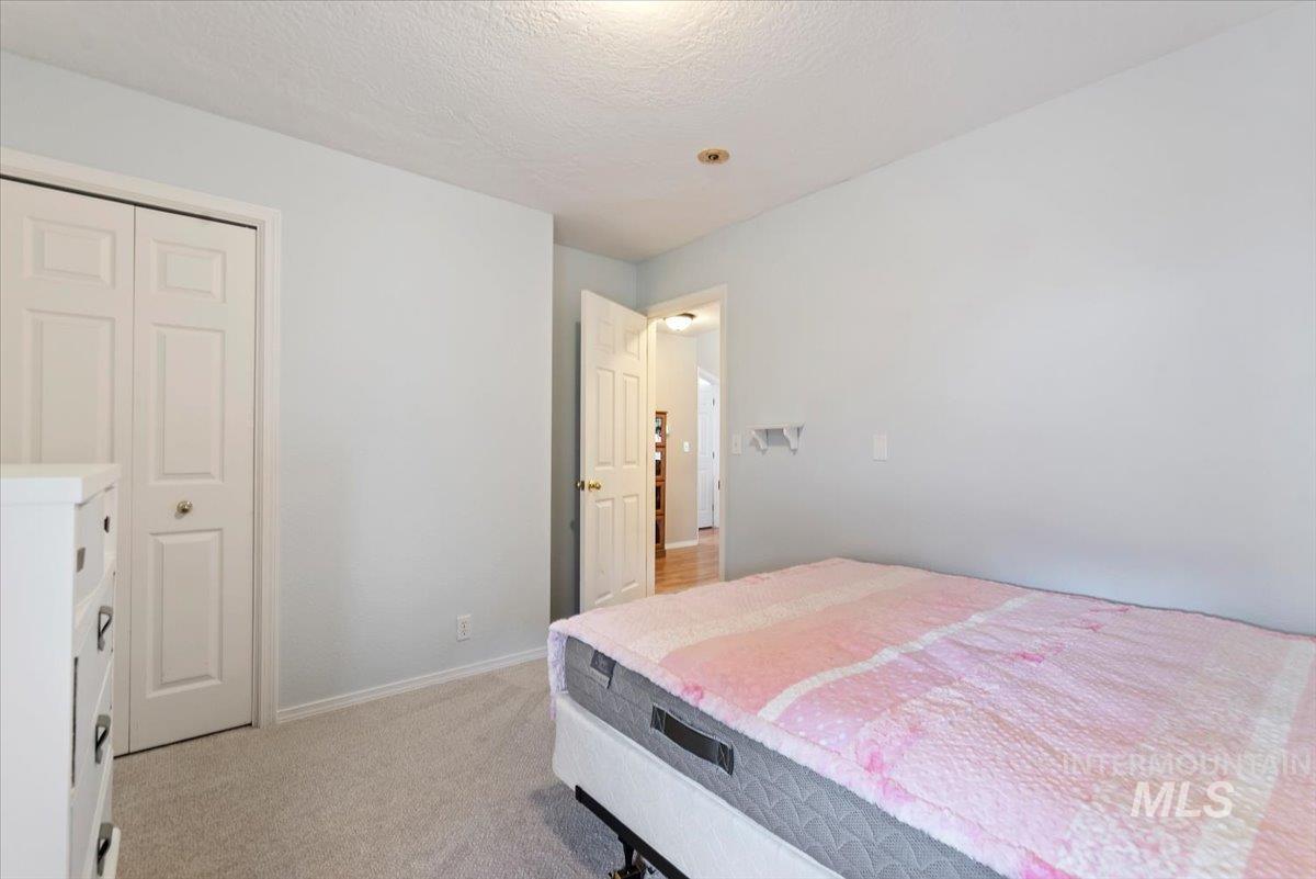 Bedroom featuring light colored carpet, a closet, and a textured ceiling