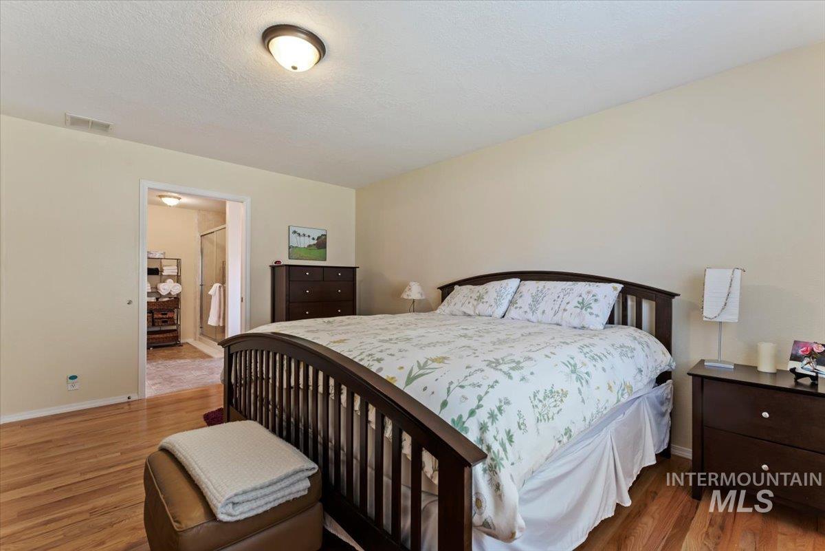 Bedroom featuring light wood-style flooring, connected bathroom, and a textured ceiling