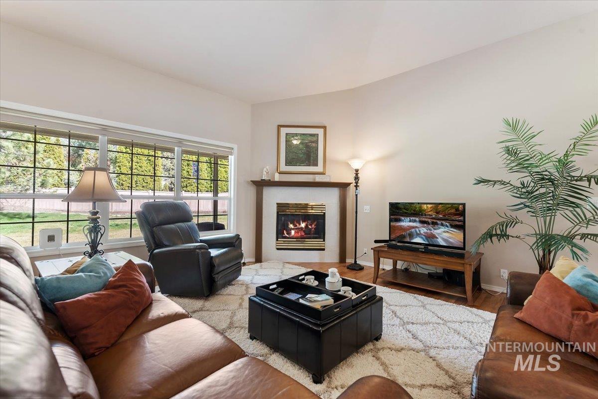Living area featuring wood finished floors, a fireplace, and vaulted ceiling