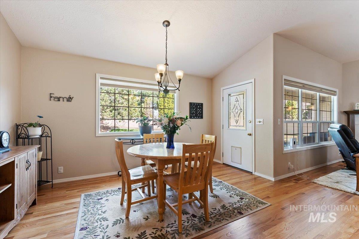 Dining room with a chandelier, light wood finished floors, and lofted ceiling