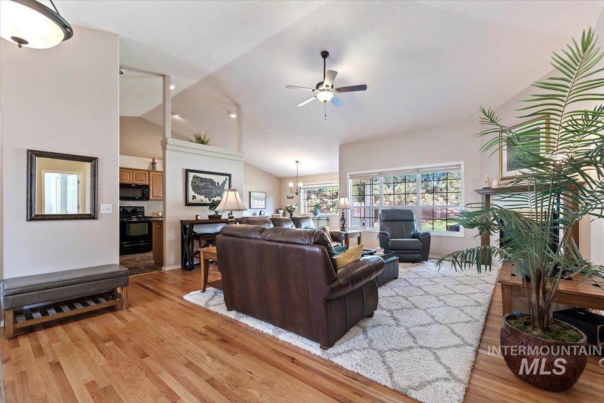 Living area with a ceiling fan, light wood-style floors, lofted ceiling, and suspended lighting