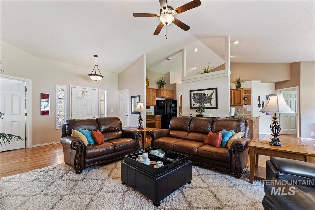 Living room with a ceiling fan, light wood-type flooring, and vaulted ceiling