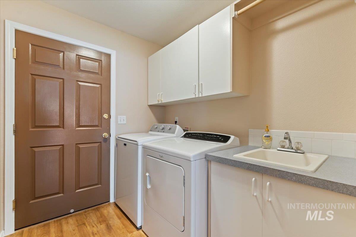Laundry area featuring independent washer and dryer, light wood-style floors, and cabinet space