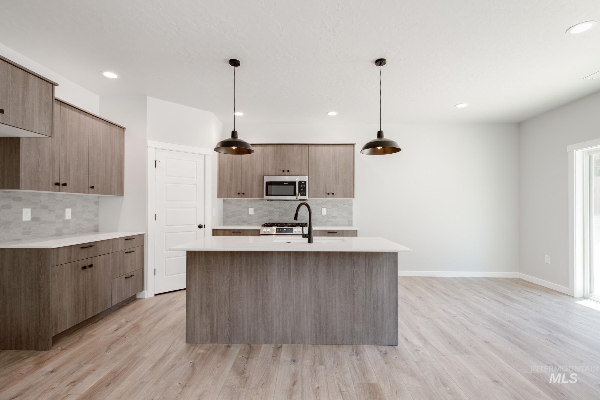 Kitchen with light stone counters, decorative light fixtures, modern cabinets, and recessed lighting