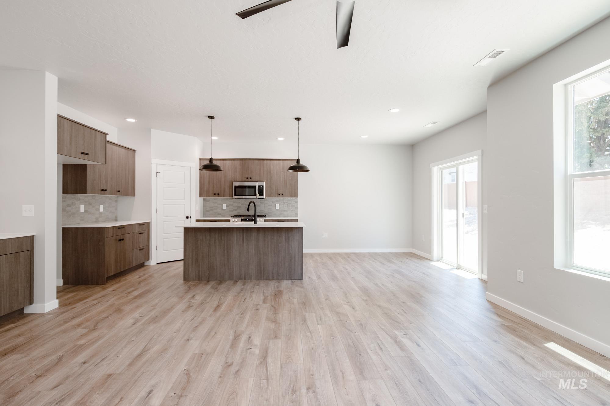 Kitchen featuring an island with sink, hanging light fixtures, modern cabinets, decorative backsplash, and recessed lighting