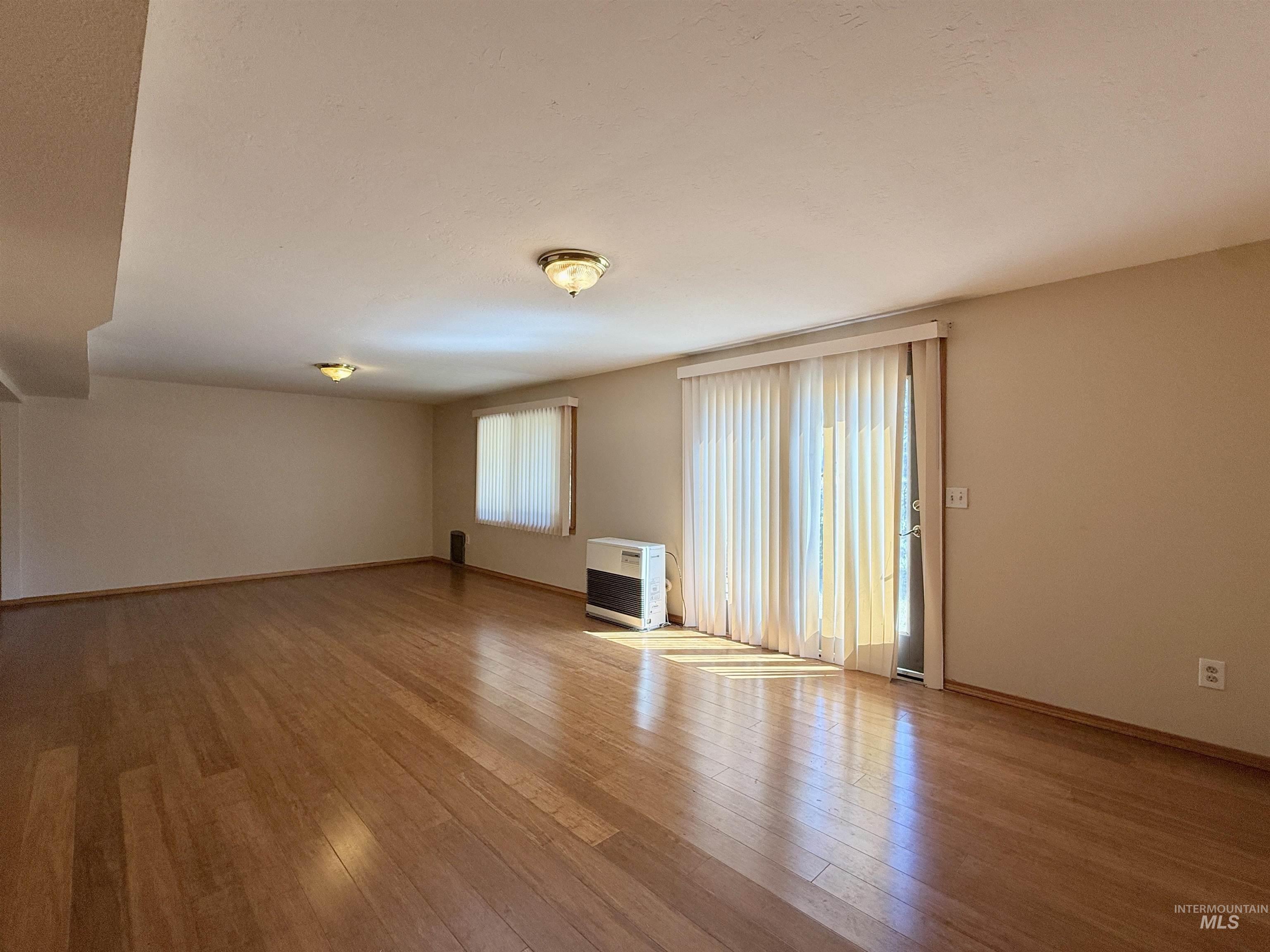 Empty room featuring hardwood / wood-style floors and heating unit