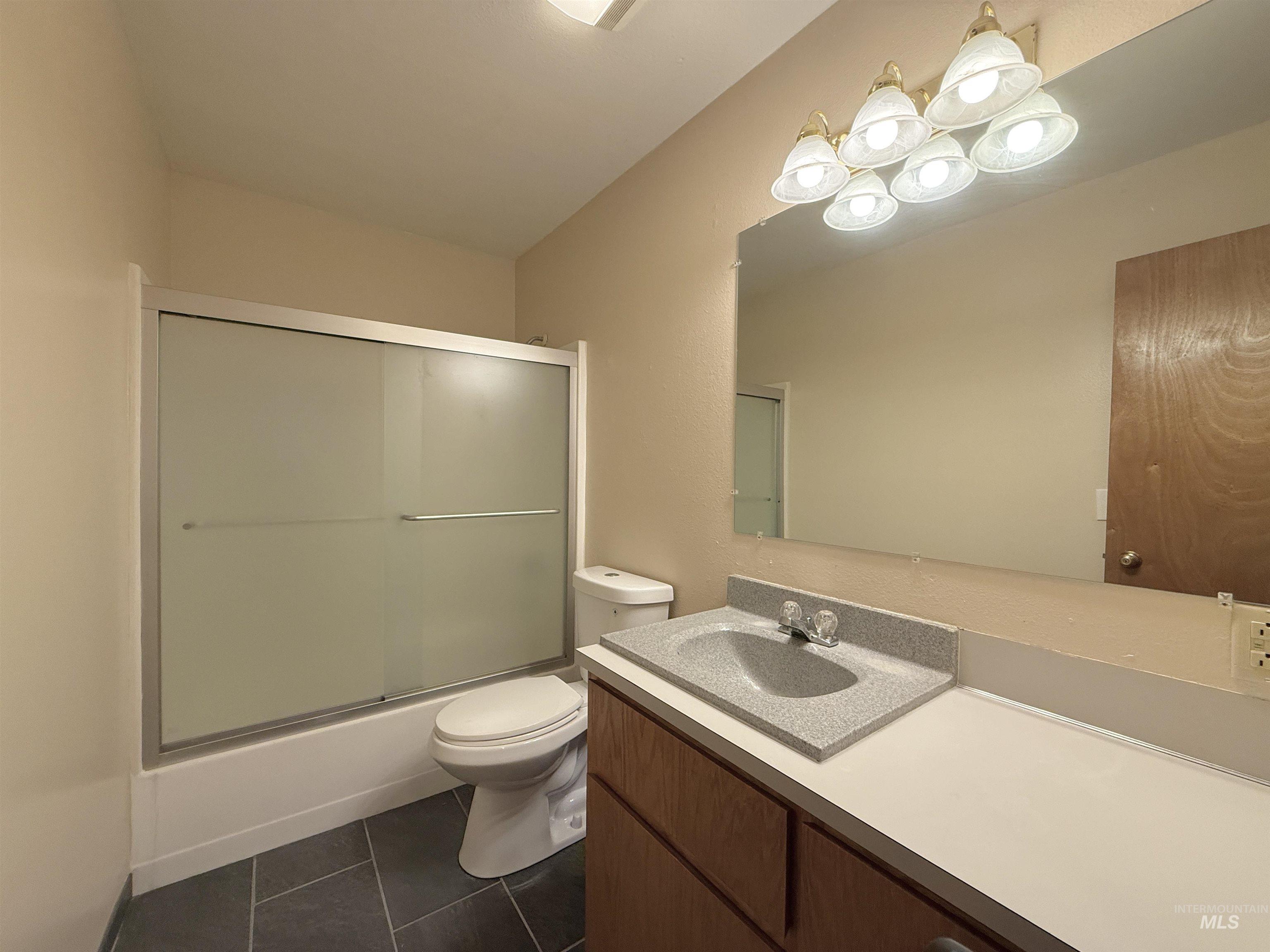 Full bathroom with vanity, tile patterned floors, and enclosed tub / shower combo