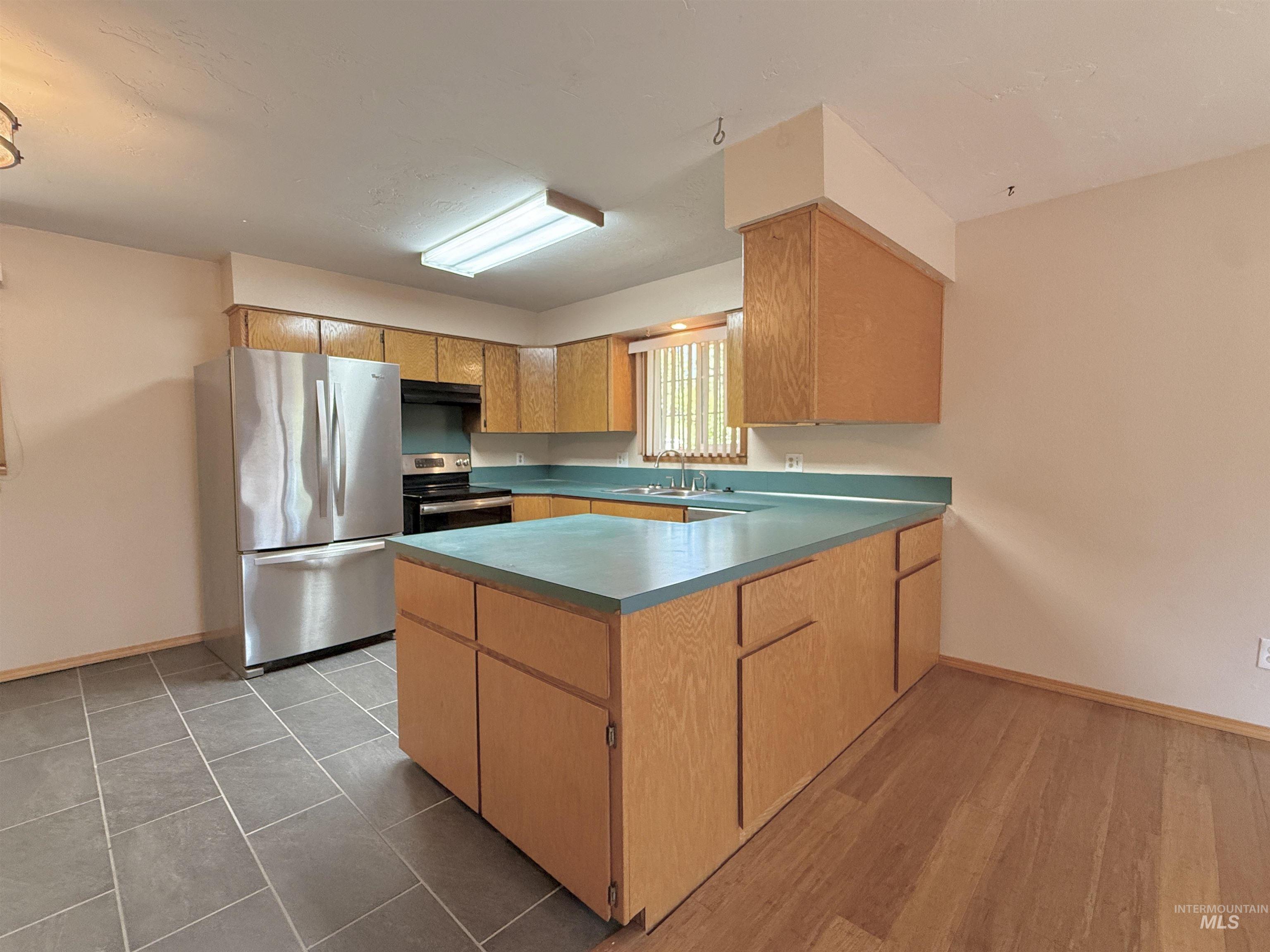 Kitchen featuring stainless steel appliances, a peninsula, and under cabinet range hood